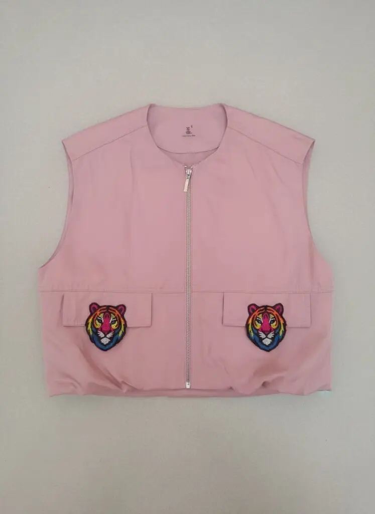Baby pink sleeveless cropped vest with two rainbow embroidered tiger face patches on the pockets