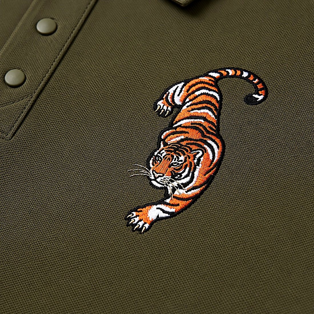 Close detail of the embroidered crawling tiger on olive fabric