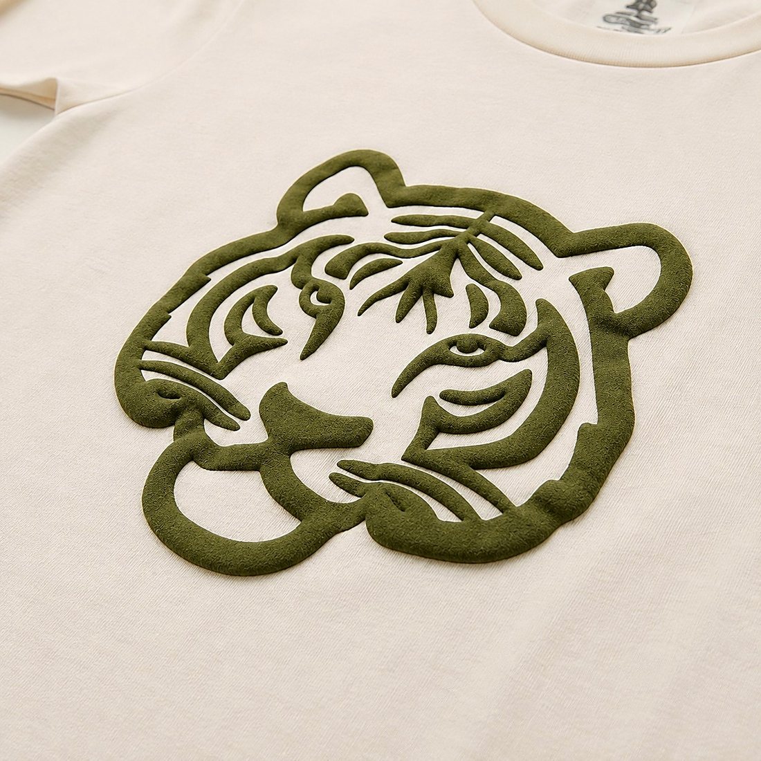 Close detail of the raised olive puff-print tiger on cream jersey