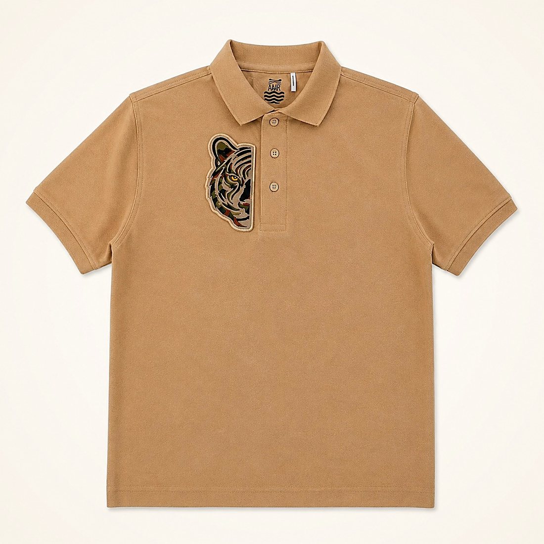 The Safari Polo in Sand — sand piqué polo with an embroidered green half tiger at the chest